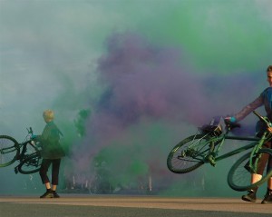 Bikes swirl in mist of purple & green smoke